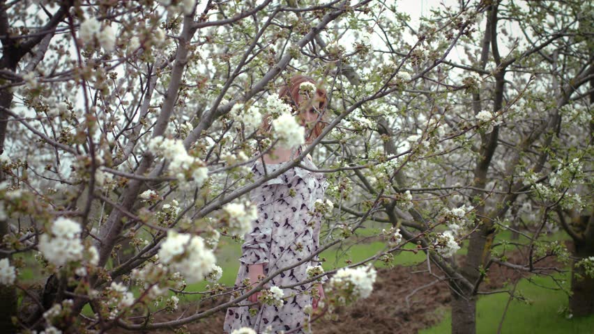 blonde girl posing near blooming trees