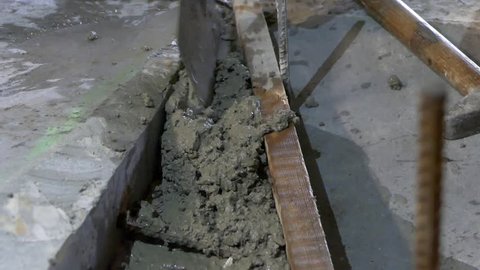 Concrete application by craftsman worker with trowel in detailed view. Sidewalk curb construction.