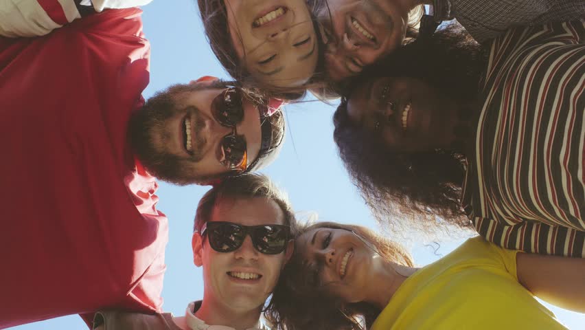 Group of friends standing in circle. Young smiling people looking down and putting their hands together in circle demonstrating closeness and friendship. Royalty-Free Stock Footage #1016072305