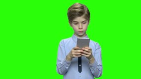 Portrait of boy with smartphone texting or playing. Green hromakey background for keying.