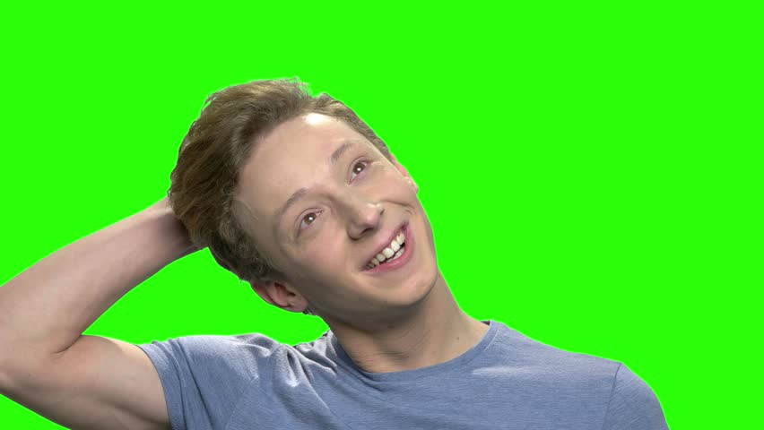 Teenage guy deaydreaming. Portrait thinking happy daydreaming teenager boy on green hromakey background.