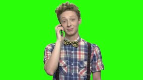 Teenager boy in checkered shirt talking with phone. Green screen hromakey background for keying.