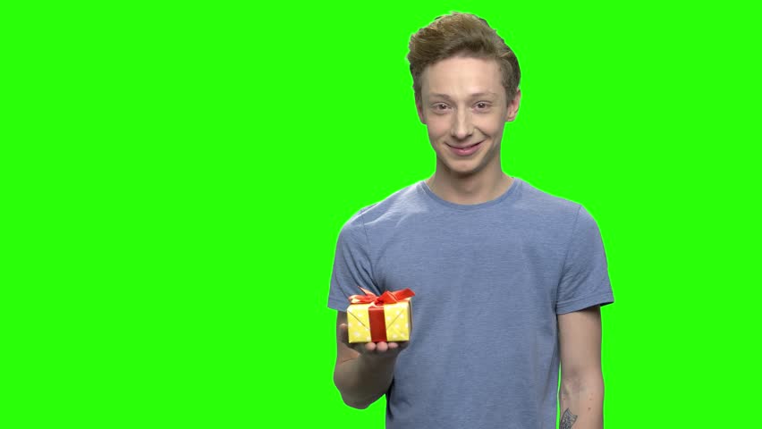 Happy teenage boy with yellow gift box. Poinntig at the present box for holiday. Green screen hromakey background for keying.