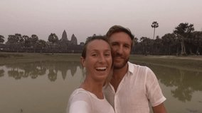 Young couple traveling take selfie portrait in front of Angkor Wat temple in Cambodia. People travel fun exploration concept 
Technology social media tourist couple enjoying vacations-slow motion