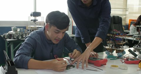 Asian student are studying electronics and measuring the signal in the electrical circuit with their teacher in classroom.