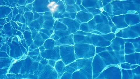 A marvelous view of sky blue waters in a swimming pool with shining web altering its shape beautifully in summer in slow motion