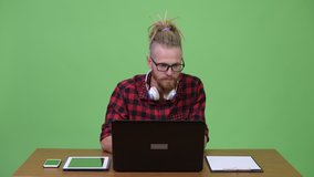 Happy bearded hipster man video calling with phone while working against wooden table