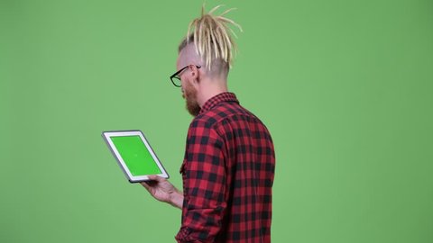 Back view of bearded hipster man with dreadlocks using digital tablet