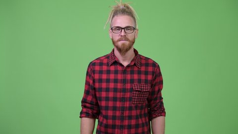 Happy handsome bearded hipster man with dreadlocks pointing to camera