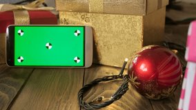 4k footage of mobile phone and Christmas decorations. Green chromakey display for inserting your image or video on screen