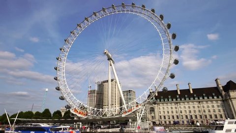 Low angle moving shot of London Eye ferris wheel over Thames River in London Great Britain 