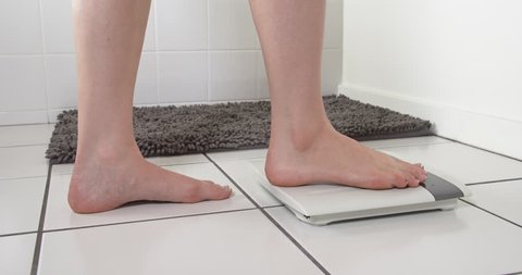 Woman Steps onto a bathroom scale.