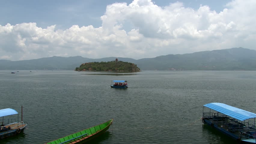Chinese boats in Fuxian Lake in Yunnan Province China. Unique mountain lake in East Asia. Landscape on background of sky with gray clouds and fog. Silence and tranquility of nature.
