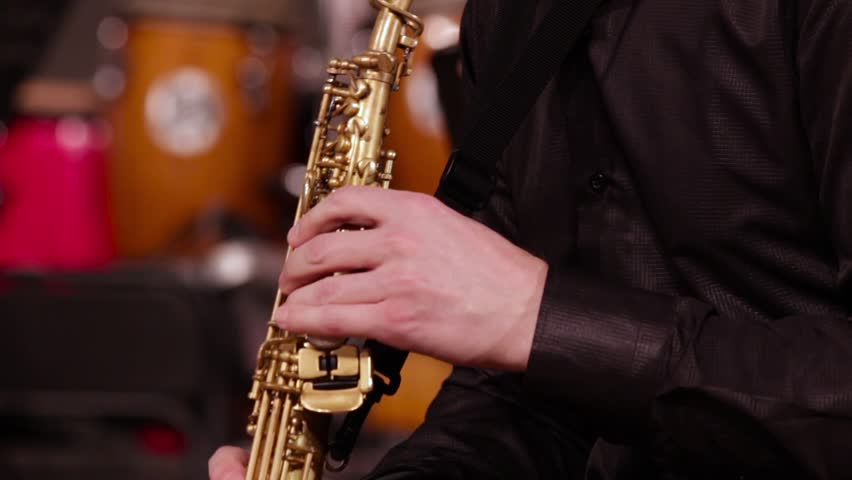 Close-up of the hands of a saxophonist on a soprano saxophone. A musician in a black shirt plays music on a wind instrument. Jazz concert. Royalty-Free Stock Footage #1016105239