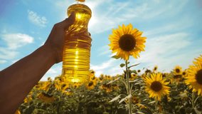 farmer holding a plastic bottle of sunflower oil in his hand field sunlight. slow motion video. blue sky background agriculture concept sunflower oil bottle farming sunset field. man lifestyle farmer
