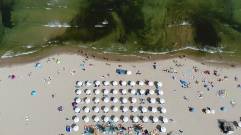 Aerial footage of the beautiful coastline of Bulgaria at the area of Sunny Beach, taken with a drone, showing people sunbathing on the beach with beach umbrellas.