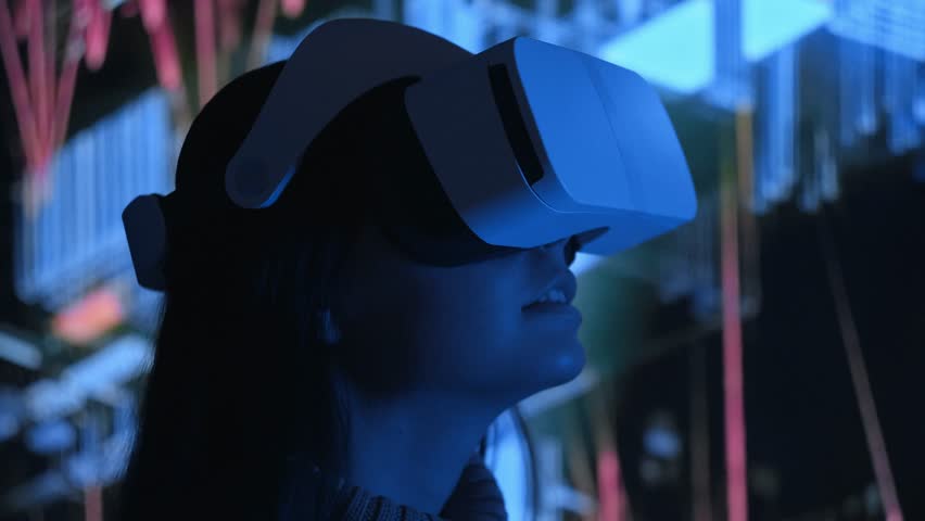 Cute young woman uses interactive VR headset, amaze and enjoys virtual reality. Wearing VR glasses or helmet to watch 360 video or play video game. Retro neon lighting, abstract background. Close up Royalty-Free Stock Footage #1016125621