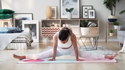 Beautiful slim woman in thirties with fair complexion does splits on mat in modern airy room with fair sophisticated interior in Scandinavian style 库存视频