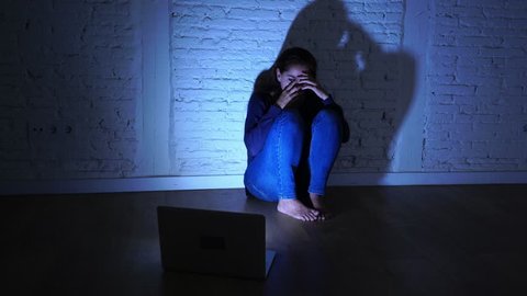 Sad and scared female Young woman with computer laptop suffering cyberbullying and harassment being online abused by stalker or gossip feeling desperate and humiliated in cyber bullying concept.