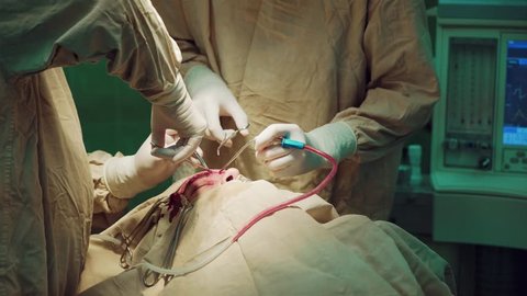 Two surgeons make operation in operating room. Working with surgical instruments