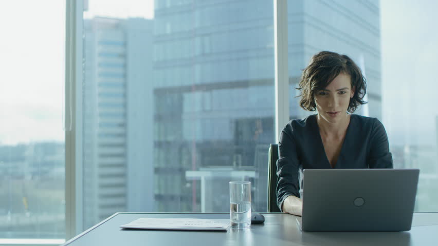 Beautiful Successful Businesswoman Working on a Laptop in Her Office with Cityscape View Window. Strong Independend Female CEO Runs Business Company. Shot on RED EPIC-W 8K Helium Cinema Camera. Royalty-Free Stock Footage #1016145739