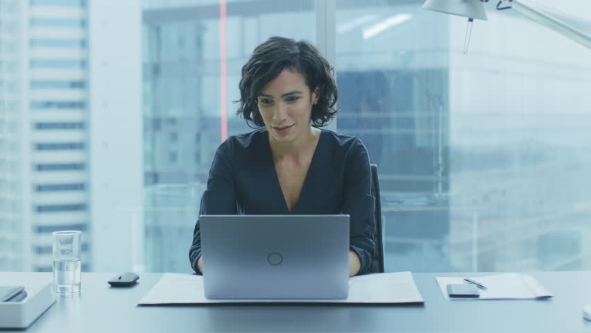 Portrait of the Successful Smiling Businesswoman Working on a Laptop in Her Office with Cityscape View Window. Beautiful Independent Female CEO Runs Company. Shot on RED EPIC-W 8K Helium Camera. Royalty-Free Stock Footage #1016145943