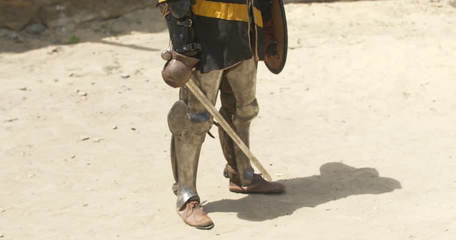 Warrior in armor with sword in hand is standing in the middle of arena