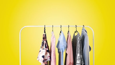Women's clothing on a white clothes hanger on yellow pastel background.