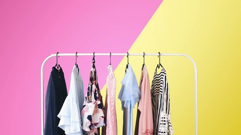 Women's clothing on a white clothes hanger on violet and yellow pastel colors background.