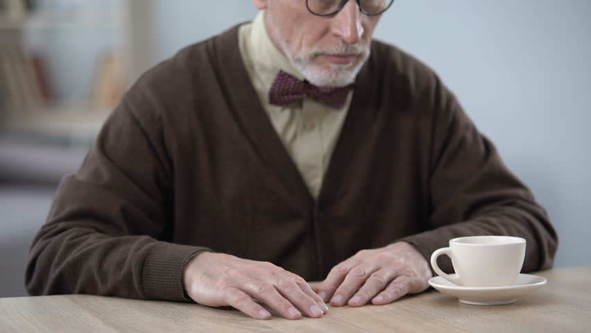 Lonely upset old man sitting at table, sad memories, social vulnerability