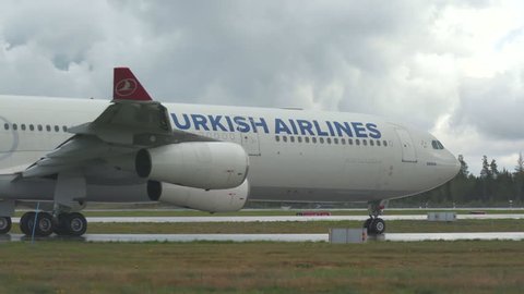 Oslo Airport Norway - ca September 2018: airplane turkish airlines huge airbus a340 passing turning low angle view panning right