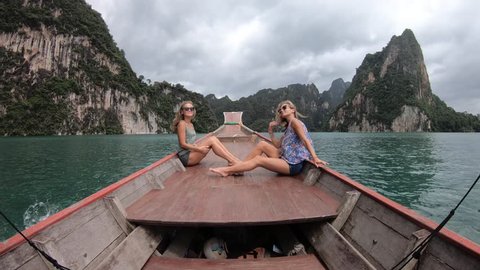 Two young woman traveler on longtail boat trip at island hopping in Cheow Lan Lake - Wanderlust and travel concept with adventure girl tourist wanderer on excursion in Thailand