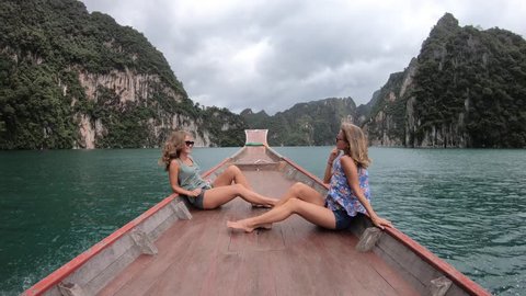 Two young women travelers on longtail boat trip at island hopping in Cheow Lan Lake - Wanderlust and travel concept with adventure girl tourist wanderer on excursion in Thailand