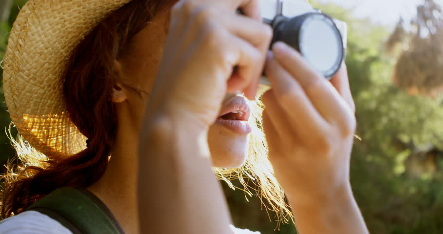 Close up of female African-american hiker clicking photos with vintage camera at countryside 
