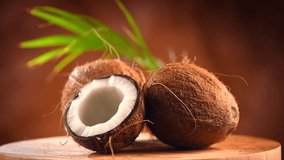 Coconut. Whole and half coco nut rotated on brown background. Fresh healthy coconut closeup. Exotic fruit. Milk or oil, cooking ingredient. 4K UHD video, slow motion