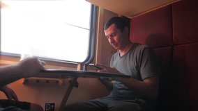 man is sitting on the train carriage holding a smartphone Railway and drinking coffee and tea. slow motion video. man writes messages lifestyle in the smartphone in the train social media. man with