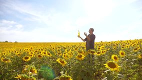 Man farmer hand hold bottle of sunflower oil the field at sunset. man shows on the production of sunflower oil in a field at sunset plastic bottle. slow motion video. man lifestyle farmer agriculture