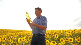 old man sunlight farmer sunflower oil concept agriculture. old man farmer holding in hand a plastic bottle sunflower oil stands in the field. lifestyle slow motion video. sunflower oil production and