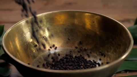 Whole and Ground black Peppercorns on old wooden table dropped pour in bowl. Peppercorn Varieties. Milled black pepper. Black pepper corns and Black pepper Powder on wooden background. Close up, slow