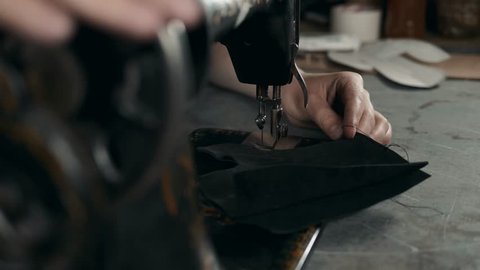 Sewing process of the leather shoes production factory bag belt. Man's hands behind sewing. Leather workshop handmade diy shoemaker