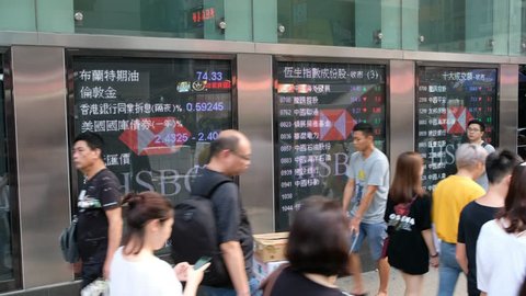 Hong Kong - August 24, 2018: Pedestrians walk past a financial display board in Mong Kok, Hong Kong, China.