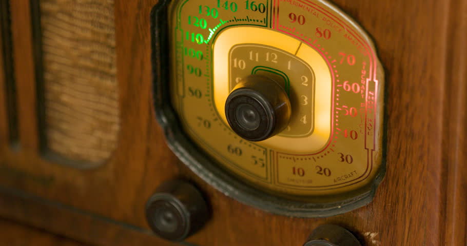Close-up of a the fingers of a Caucasian male carefully and patiently locating a good signal on his vintage radio.