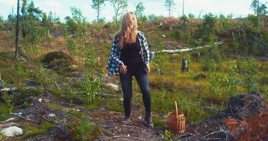 A girl dances near a basket in the forest.