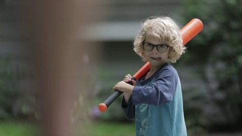 Confident boy playing baseball with father at yard