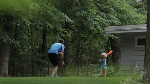 Cheerful boy playing baseball with father at yard