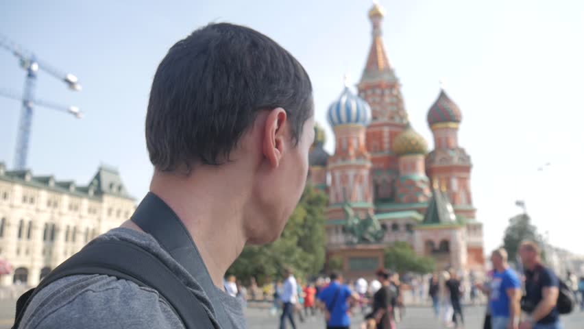 Happy young man use the phone for reference on Red Square in Moscow, 