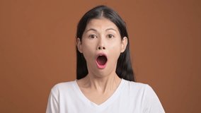 Surprise and shock woman isolated. Portrait of asian woman in white t-shirt with shocking face expression looking at camera.
