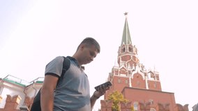 Travel and technology. Happy tourist man looks the navigator smartphone taking selfie with backpack. slow motion video. on Red Square in Moscow, Russia. tourist journey travel man in Russia lifestyle