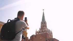 Travel and technology. lifestyle Happy tourist man looks the navigator smartphone taking selfie with backpack. slow motion video. on Red Square in Moscow, Russia. tourist journey travel man in Russia