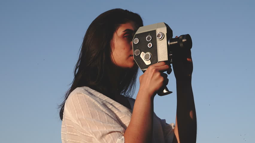 girl cameraman shoots in the evening on the open air. End of summer season, August.